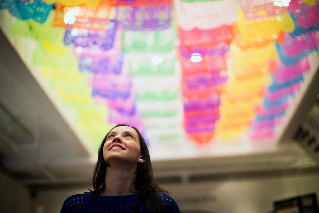 woman looking up at an art installation on the ceiling - bright colors shown
